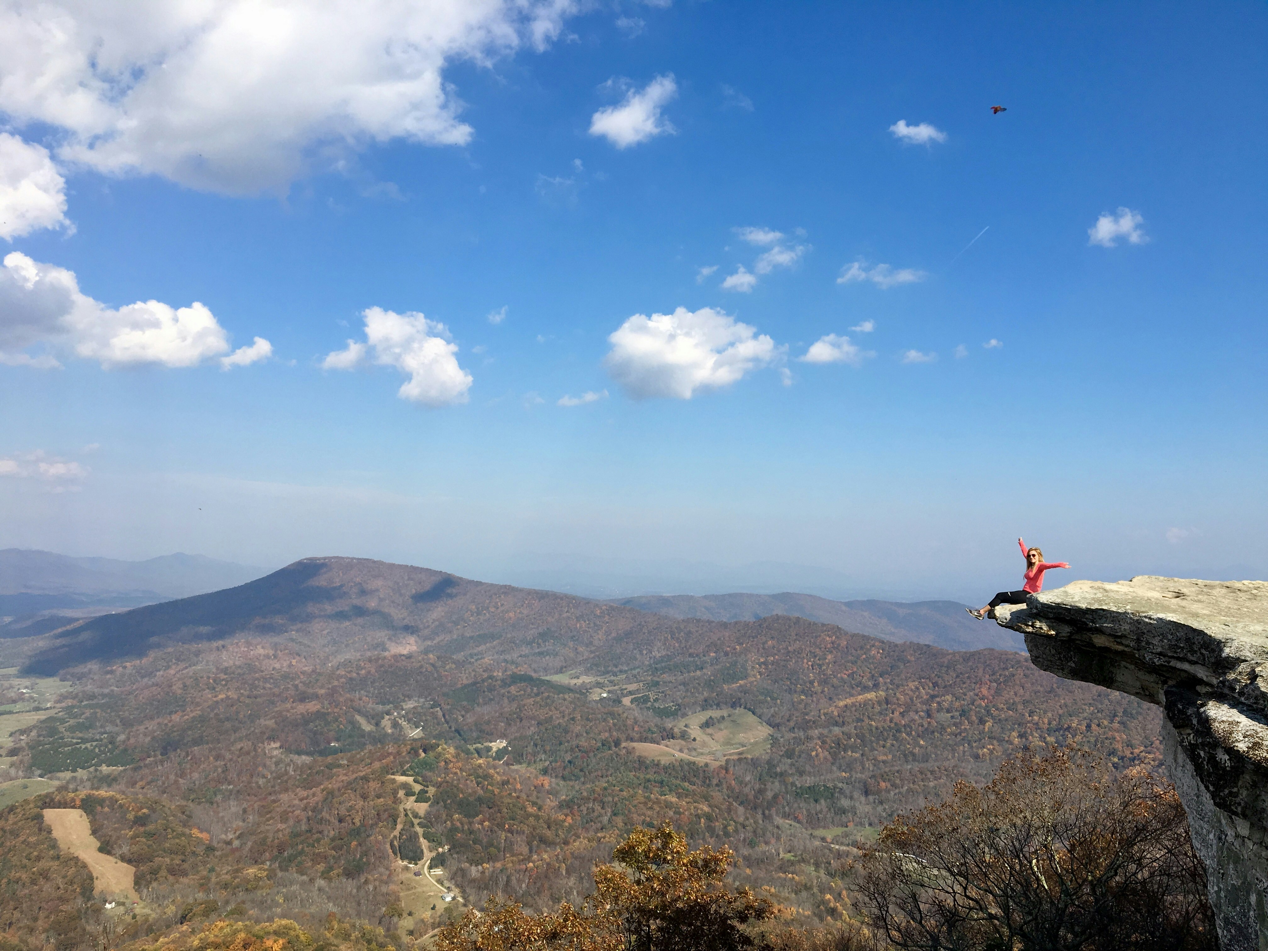 aerial photo of person sitting on cliff during daytime